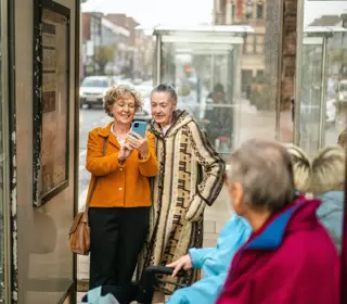 Two people looking at phone at bus stop