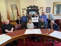 People sitting around a table, holding up the disability impact pledge.