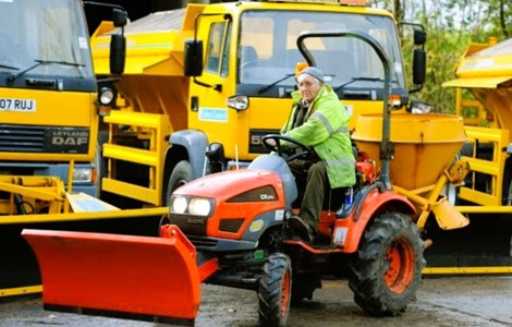 person on tractor in front of gritting lorries