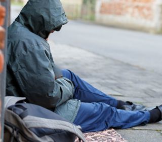 Homeless person sitting on pavement