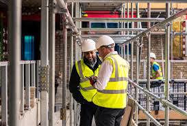 men in high vis looking at plans