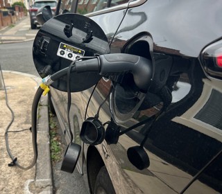 An electric car being charged. In the background you can see the wire going to the street light. 