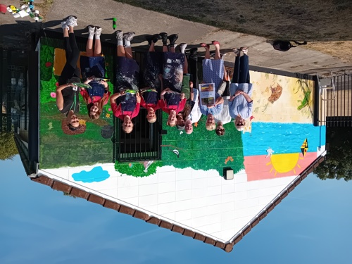 Students, an artist and ward members standing in front of a mural