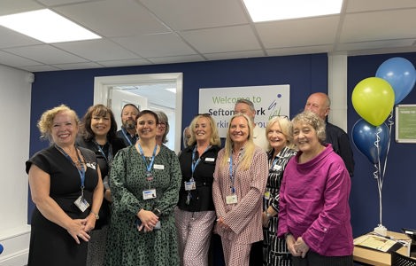 Group of people from the Sefton@Work team and Cllr Paulette Lappin in an office setting, smiling. Celebratory balloons are on the desk. 