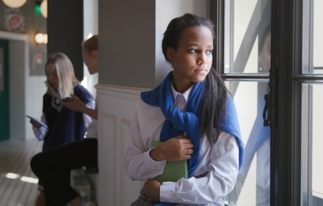 A student looking out the window holding a book