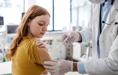Doctor injecting vaccine into a teenage girl's arm.