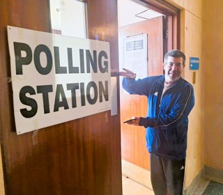 Person with sign that says 'Polling Station'