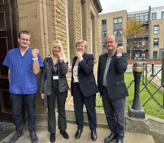 four people standing wearing wristbands