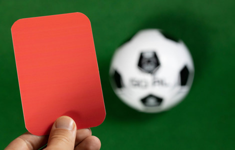 Hand holding red card football in background